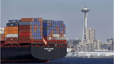 FILE - In this Feb. 15, 2015 file photo, the Space Needle towers in the background beyond a container ship anchored in Elliott Bay near downtown Seattle.