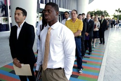 FILE - In this Wednesday, Oct. 23, 2013 file photo, Luis Mendez, 23, left, and Maurice Mike, 23, wait in line at a job fair held by the Miami Marlins, at Marlins Park in Miami.