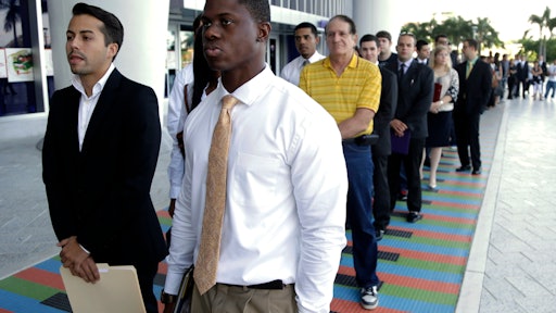 FILE - In this Wednesday, Oct. 23, 2013 file photo, Luis Mendez, 23, left, and Maurice Mike, 23, wait in line at a job fair held by the Miami Marlins, at Marlins Park in Miami.