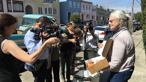 Resident Julie O’Keefe shows off the box of pastries one robot’s lid popped open to reveal for the crowd.