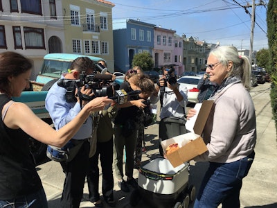 Resident Julie O’Keefe shows off the box of pastries one robot’s lid popped open to reveal for the crowd.