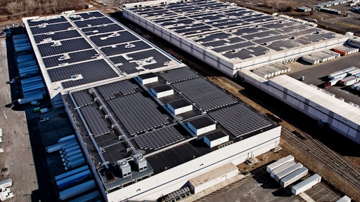 Aerial view of two Amazon fulfillment facilities with solar systems on their rooftops.