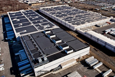 Aerial view of two Amazon fulfillment facilities with solar systems on their rooftops.