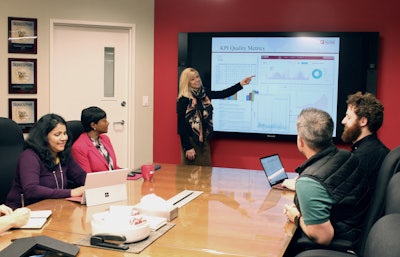 Lisa Dolan (pictured standing center), Vice President of Supply Chain Strategy consistently pushes the boundaries of technology innovation and database integration to develop real-time supply chain visibility tools that achieve best in class operational performance results for ALOM customers.