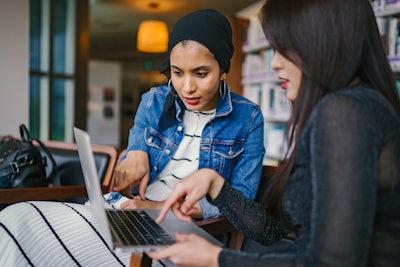 Two Women Looking And Pointing At Macbook Laptop 1569076