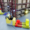 Warehouse facility with yellow and red forklifts operating near burgundy pallet racks stacked with cardboard boxes.