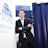 Professional man in dark blazer and white shirt standing confidently with arms crossed in front of blue shipping containers and company signage Headshot