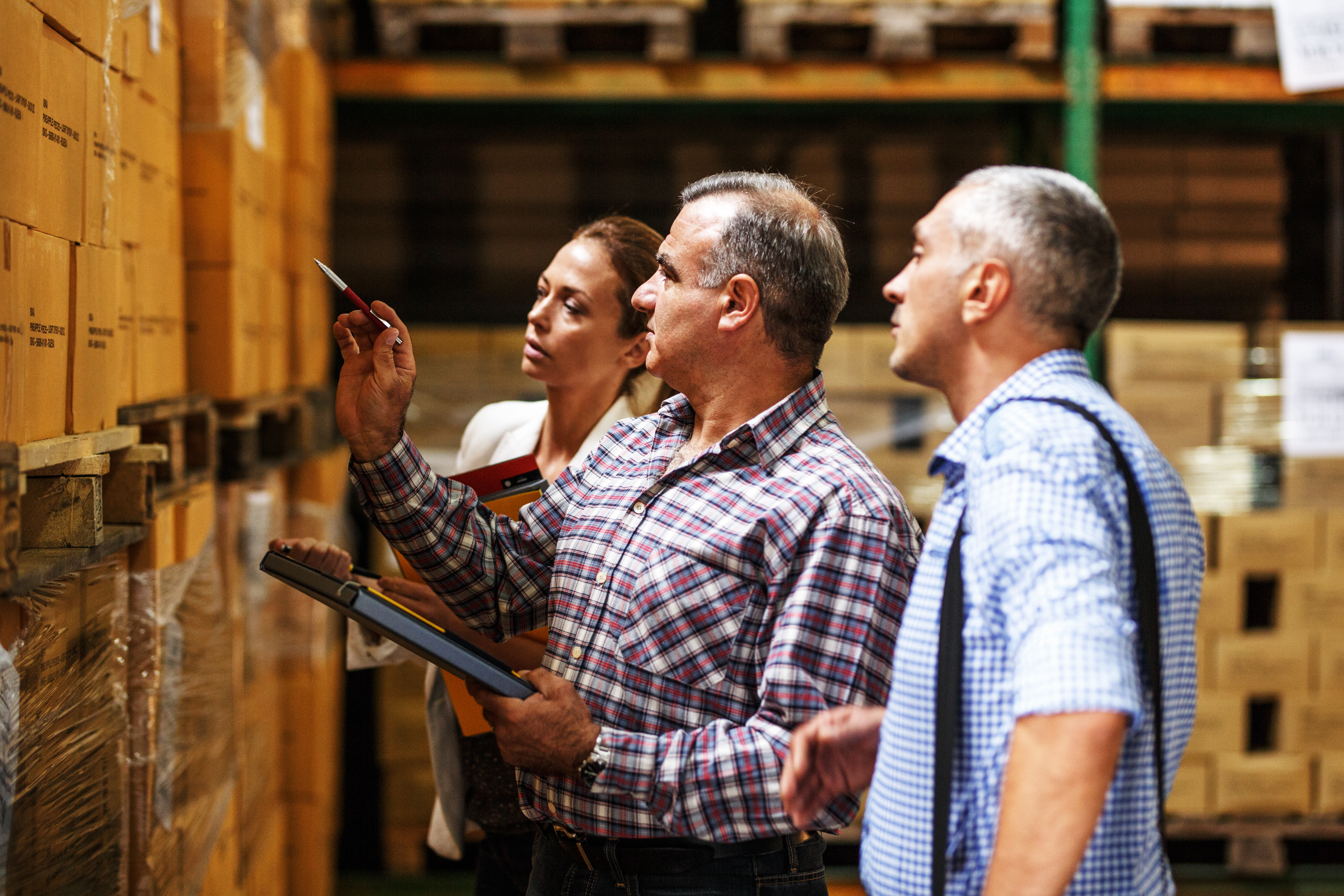 Warehouse workers reviewing inventory boxes on shelves in a storage facility