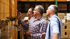 Warehouse workers reviewing inventory boxes on shelves in a storage facility