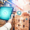 Worker holding tablet with digital logistics icons in warehouse with stacked boxes