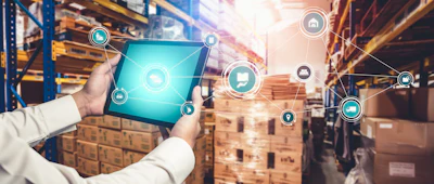 Worker holding tablet with digital logistics icons in warehouse with stacked boxes