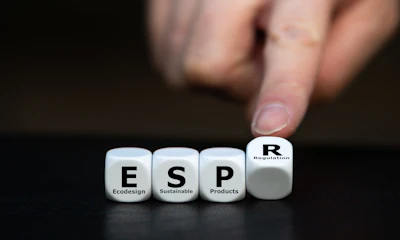 Hand pointing to white cubes spelling ESP (Ecodesign Sustainable Products) with R Regulation cube on dark surface