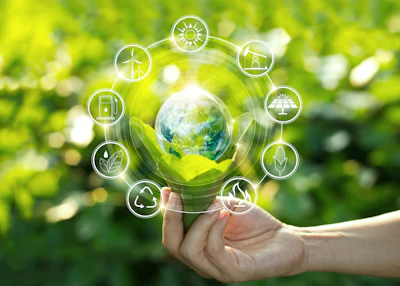 Hand holding a glowing globe surrounded by renewable energy and sustainability icons including solar, wind, hydro, and recycling symbols on green nature background