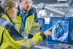 Two engineers in yellow safety vests reviewing 3D CAD design on computer monitor in industrial facility