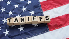 Wooden letter tiles spelling 'TARIFFS' arranged on the American flag background