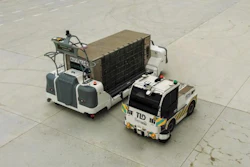 Two airport ground support vehicles parked on concrete apron, including a white tug and tow tractor