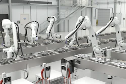 Industrial robotic assembly line with white mechanical arms processing components on a production conveyor in a modern factory facility.