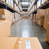 Industrial warehouse aisle lined with stacked cardboard boxes on blue and yellow metal shelving units