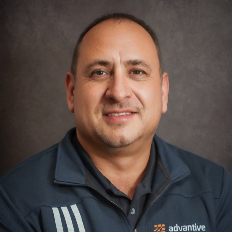 Professional headshot of man in navy Advantive branded jacket against gray background Headshot