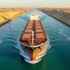 Large red and black cargo ship navigating through the Suez Canal with sandy desert banks on both sides