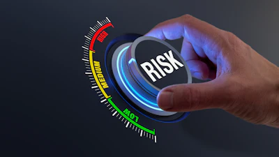 Hand adjusting risk management gauge dial with color-coded severity scale from green to red