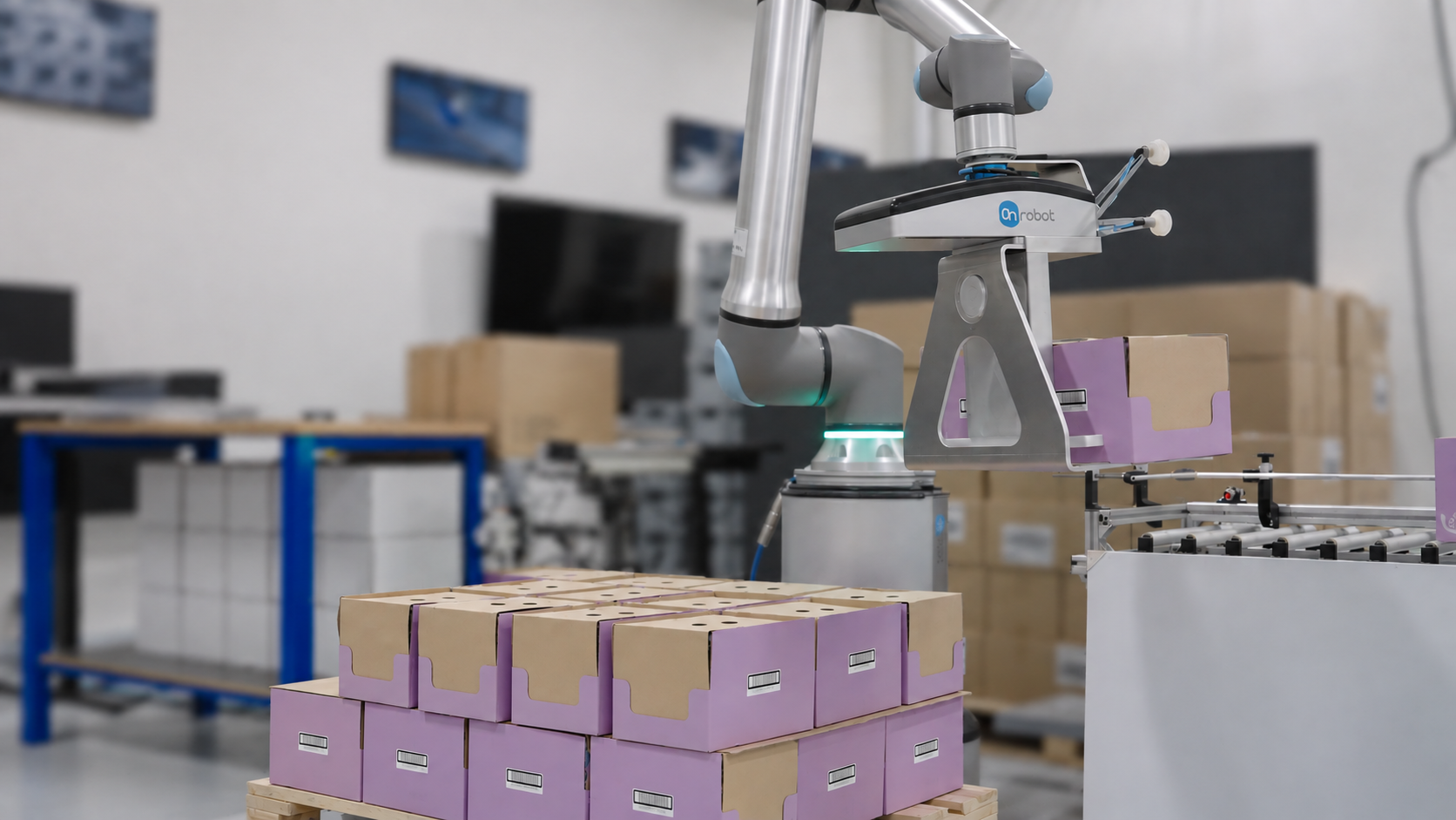 Collaborative robot arm sorting purple and brown cardboard boxes in a warehouse facility