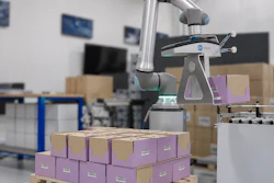Collaborative robot arm sorting purple and brown cardboard boxes in a warehouse facility