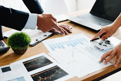 Business professionals analyzing financial charts and data during a collaborative meeting at a wooden desk