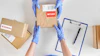 Worker in blue gloves handling cardboard boxes marked with return label and shipping documentation