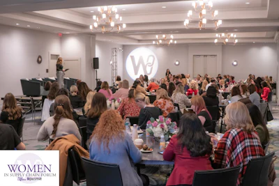 Women in Supply Chain Forum conference with attendees seated at tables facing a stage presentation.